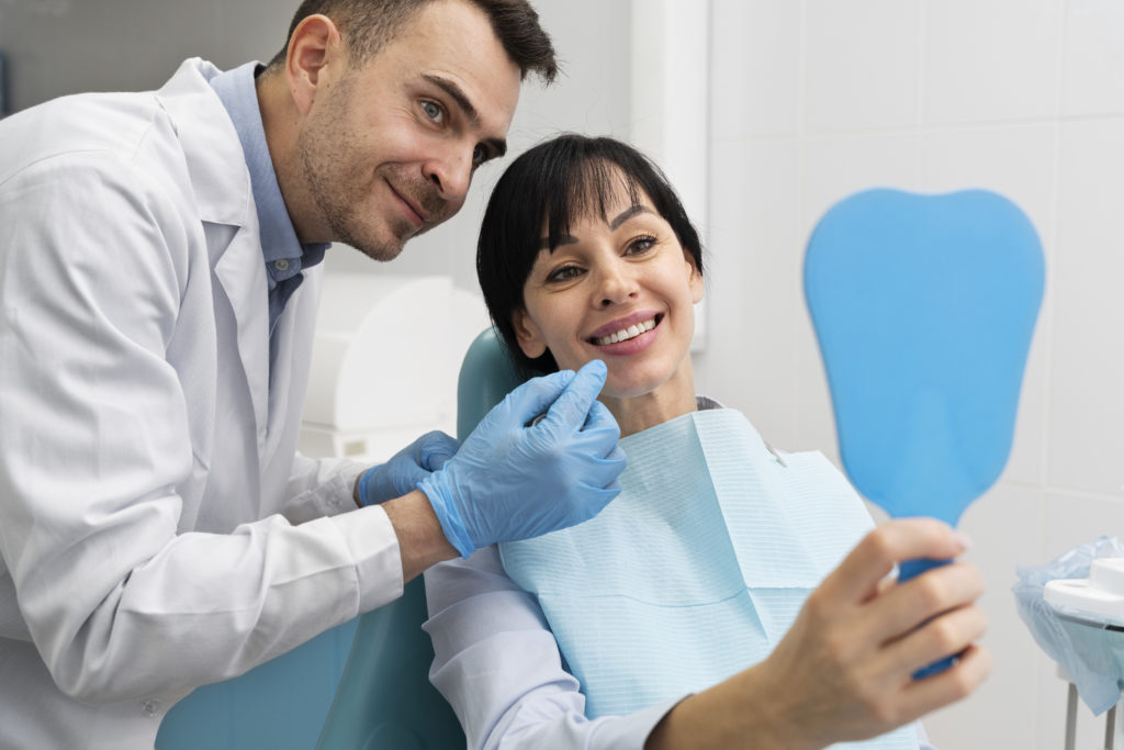 Doctor and smiling patient looking in a hand mirror, happy because they use Rubicare Plans