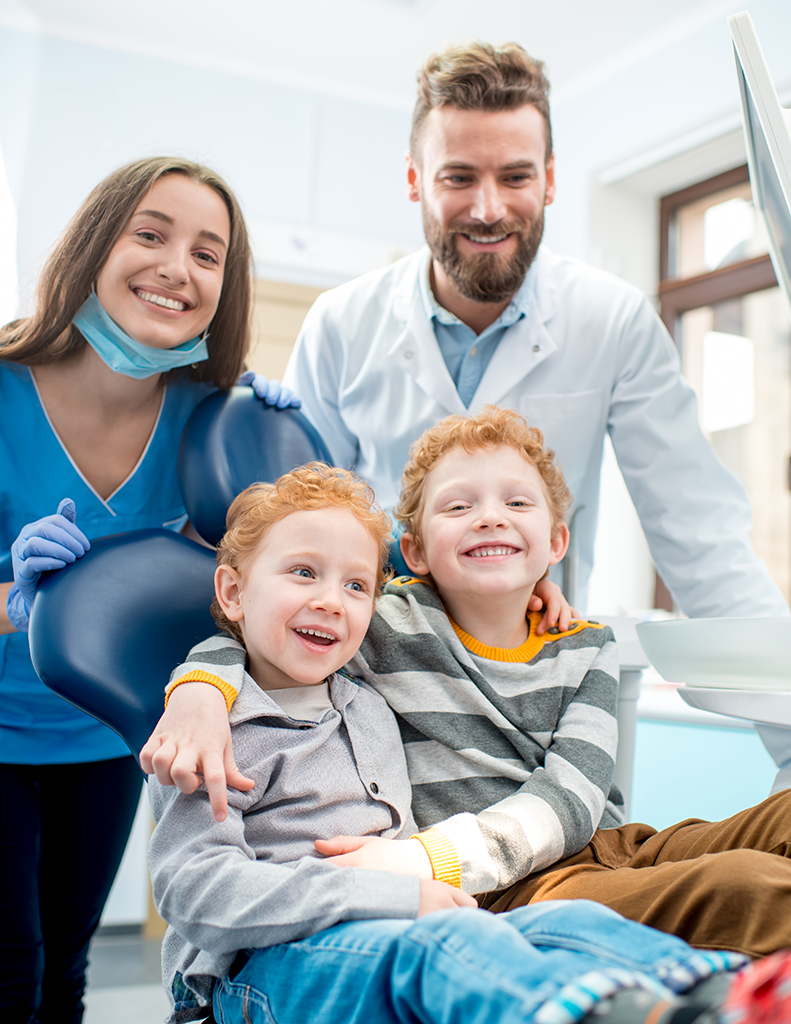 Rubicare for Individuals & Families. Twin boys smile in dental chair as Rubicare providers look on in the background.